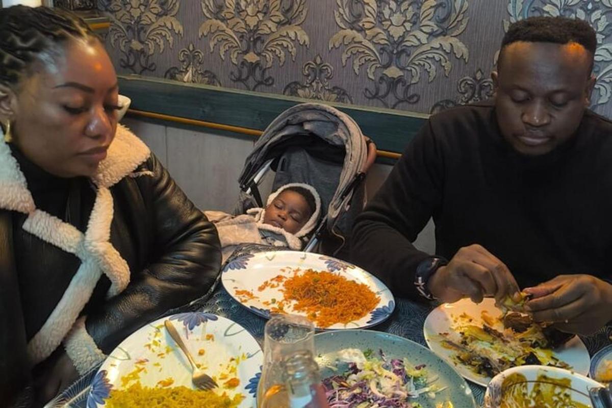 dua orang dewasa dan seorang bayi duduk di meja dengan pinggan makanan