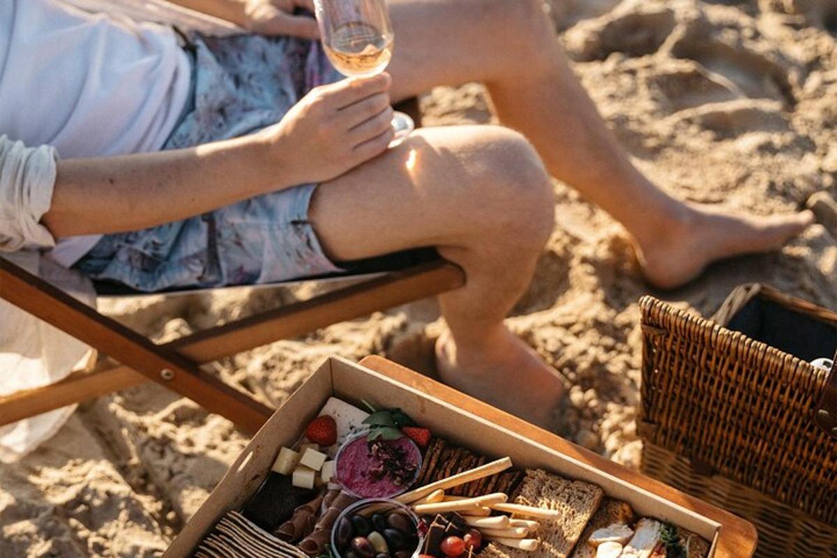 una mujer sentada en una playa con una copa de vino