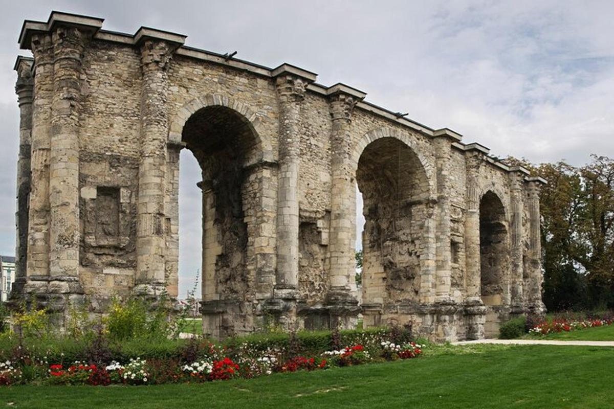 un antic edifici de pedra amb tres arcs i flors