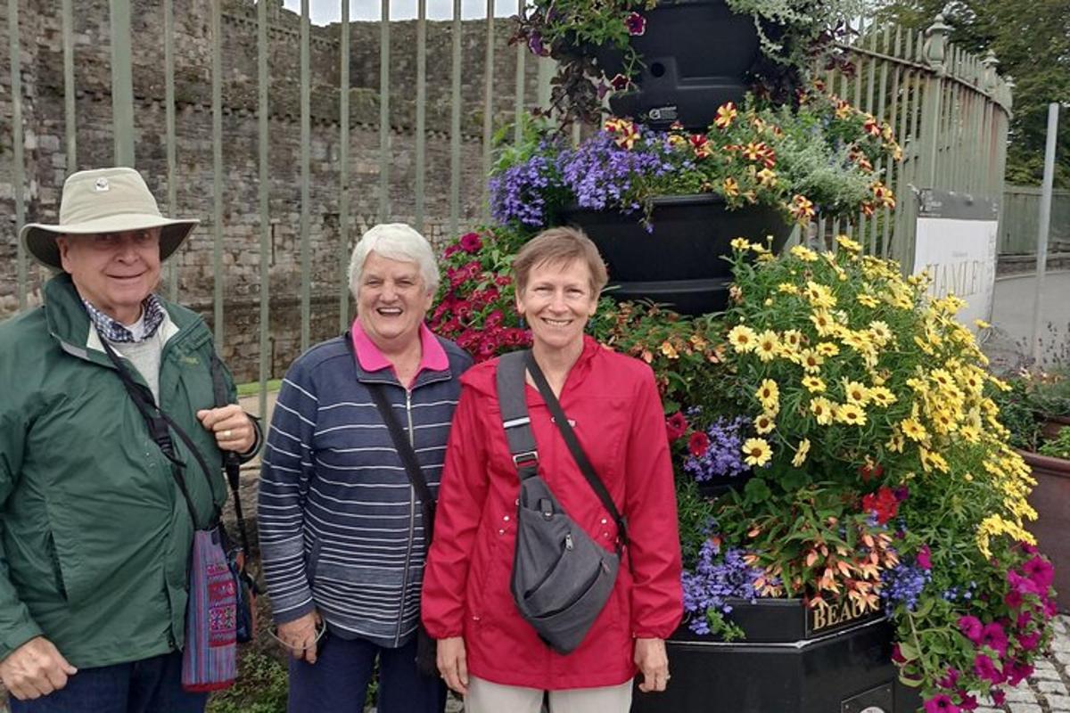 three older women standing in front of a flower garden