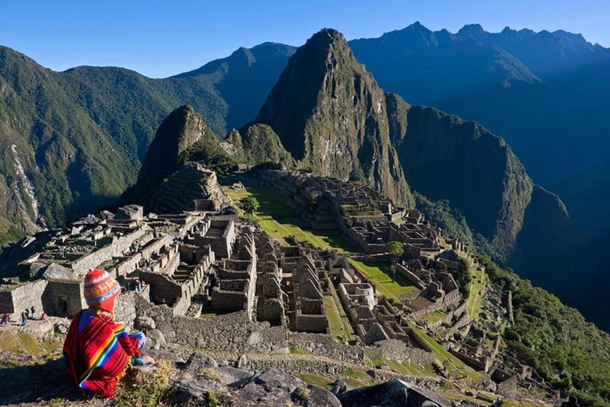 una persona seduta sul bordo di una montagna che guarda le rovine