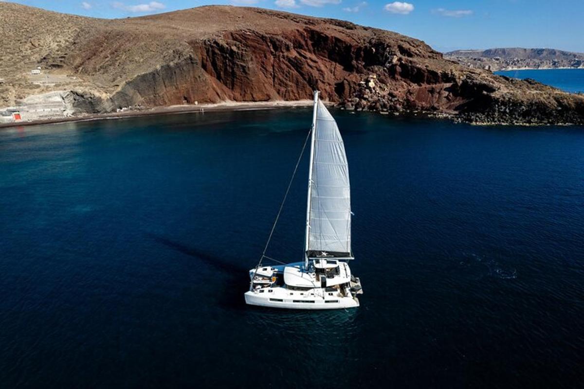 una barca a vela bianca in acqua vicino a una spiaggia