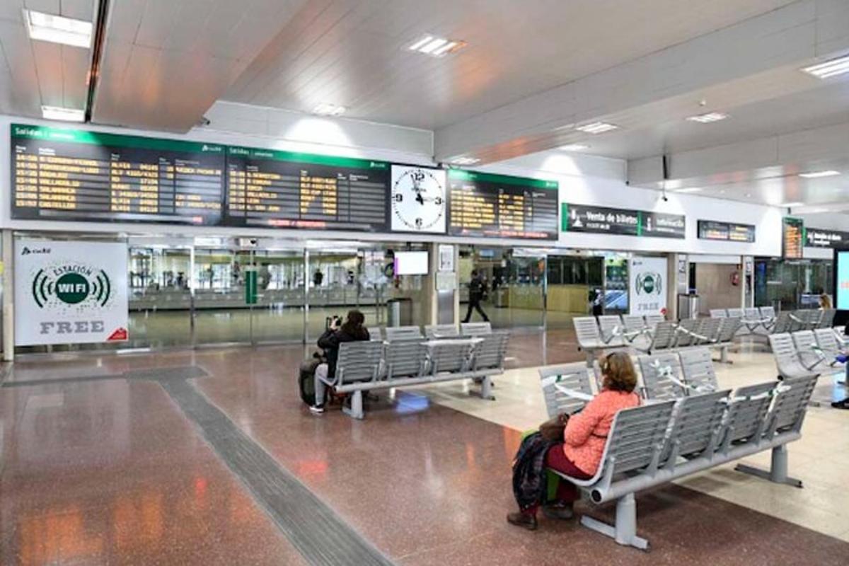 dvaja ľudia sediaci na lavičkách v letiskovom termináli