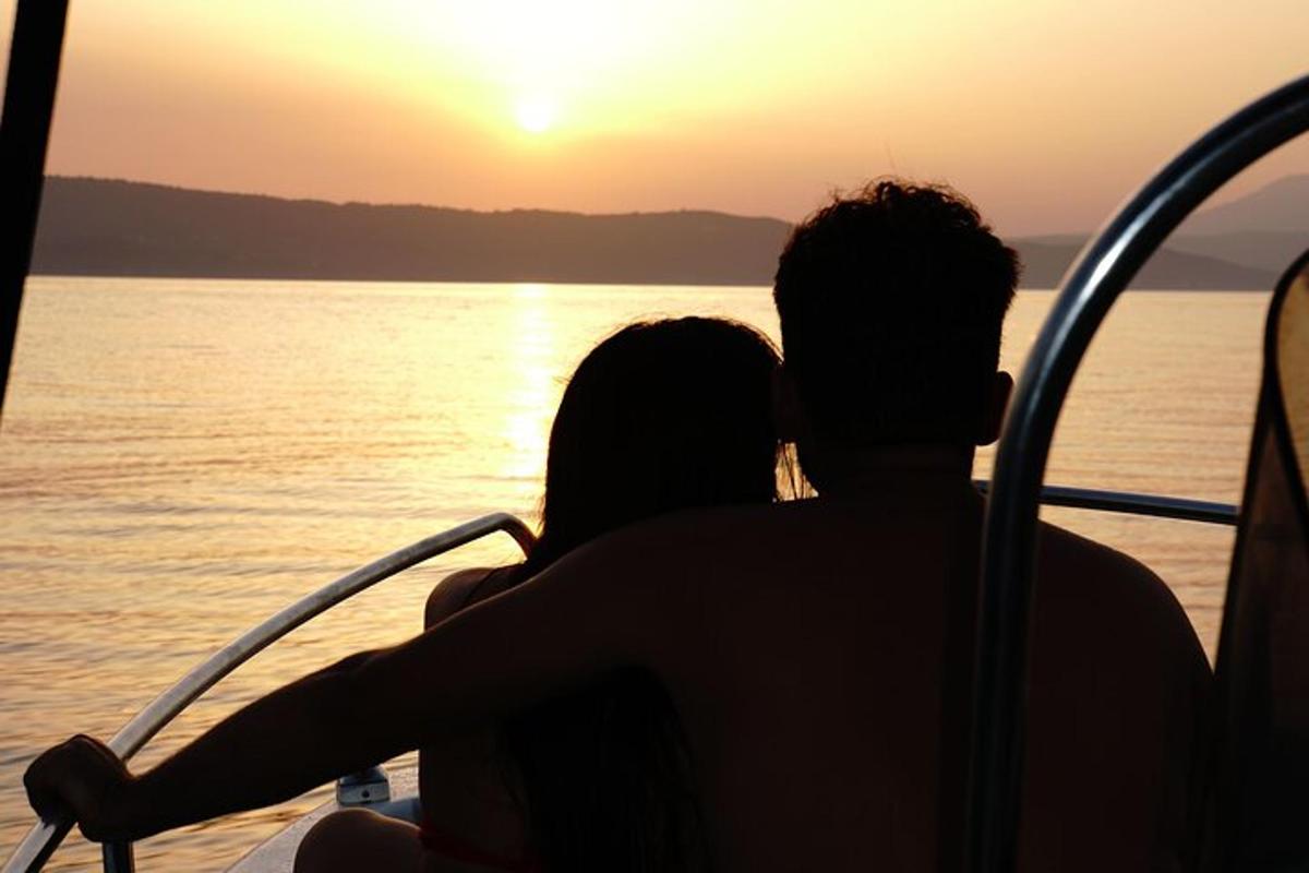 a couple sitting on a boat watching the sunset