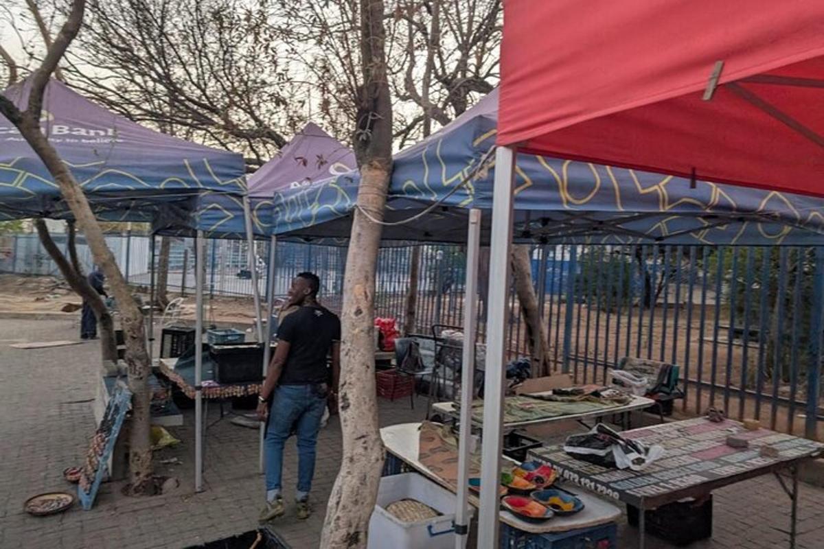 un uomo in piedi davanti a un mercato con gli ombrelli