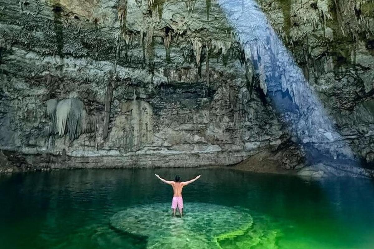 una persona dempeus a l'aigua davant d'una cascada