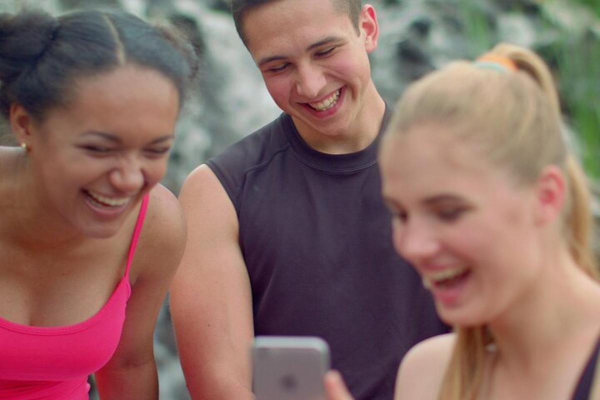 un uomo e due donne guardano un cellulare