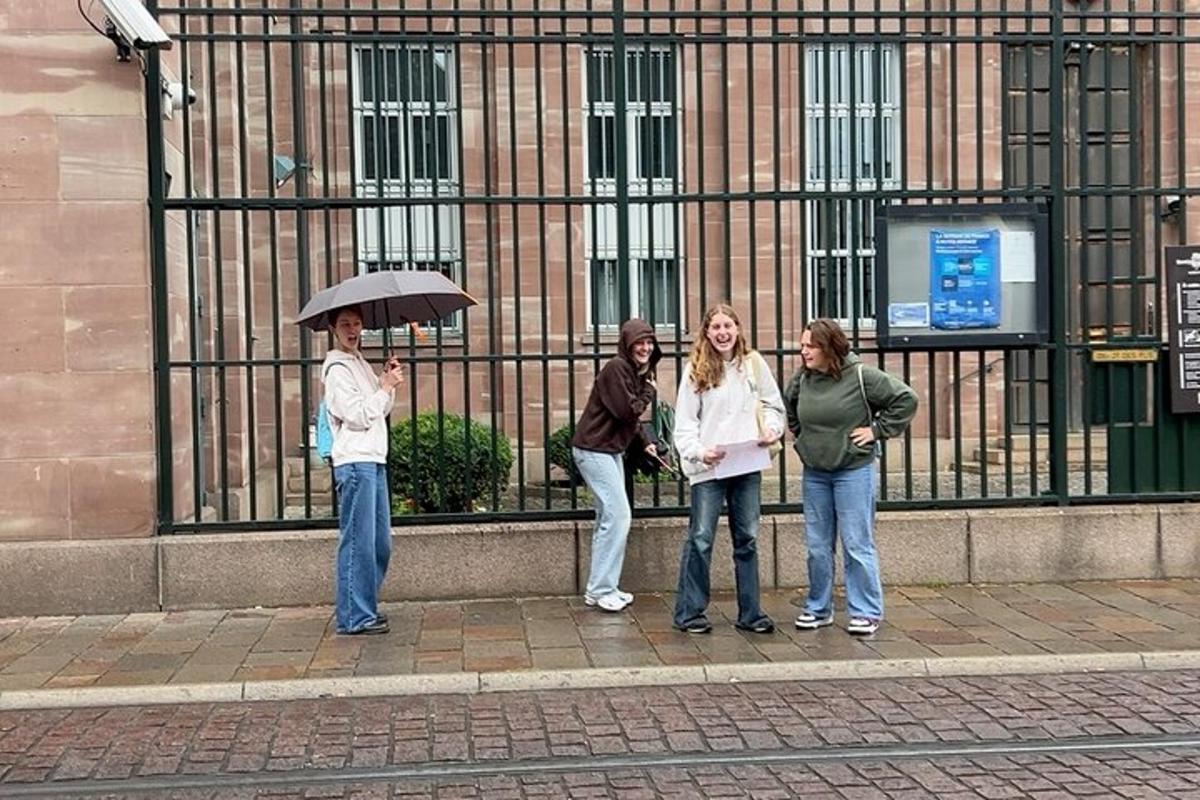 een groep mensen die met een paraplu op de stoep staan