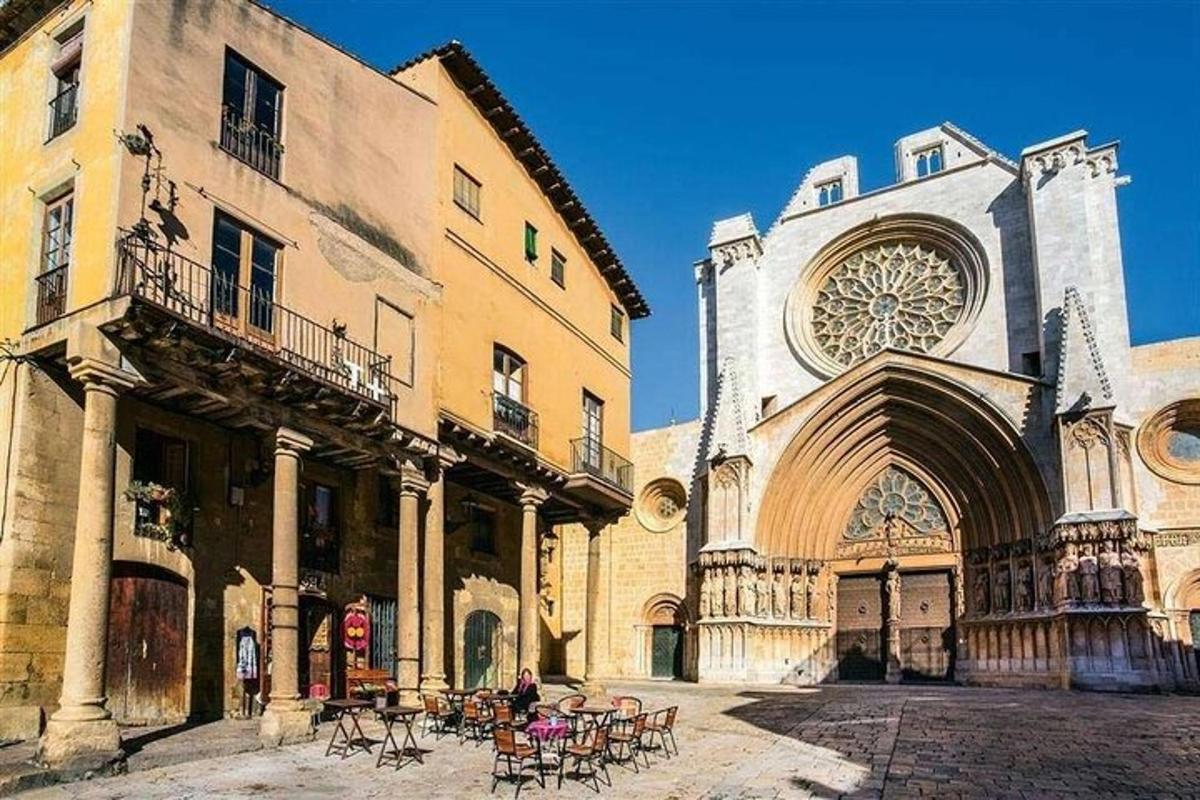 un edificio con una torre dell'orologio, tavoli e sedie