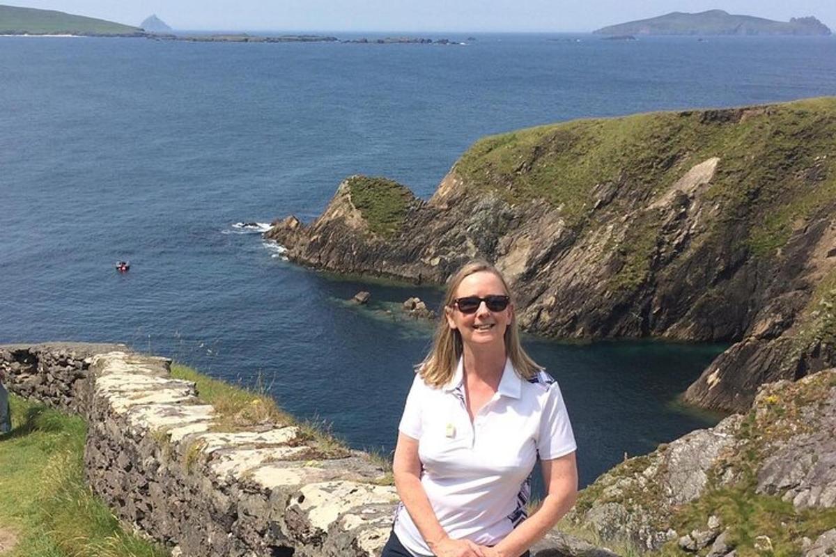 uma mulher em pé em um muro próximo ao oceano