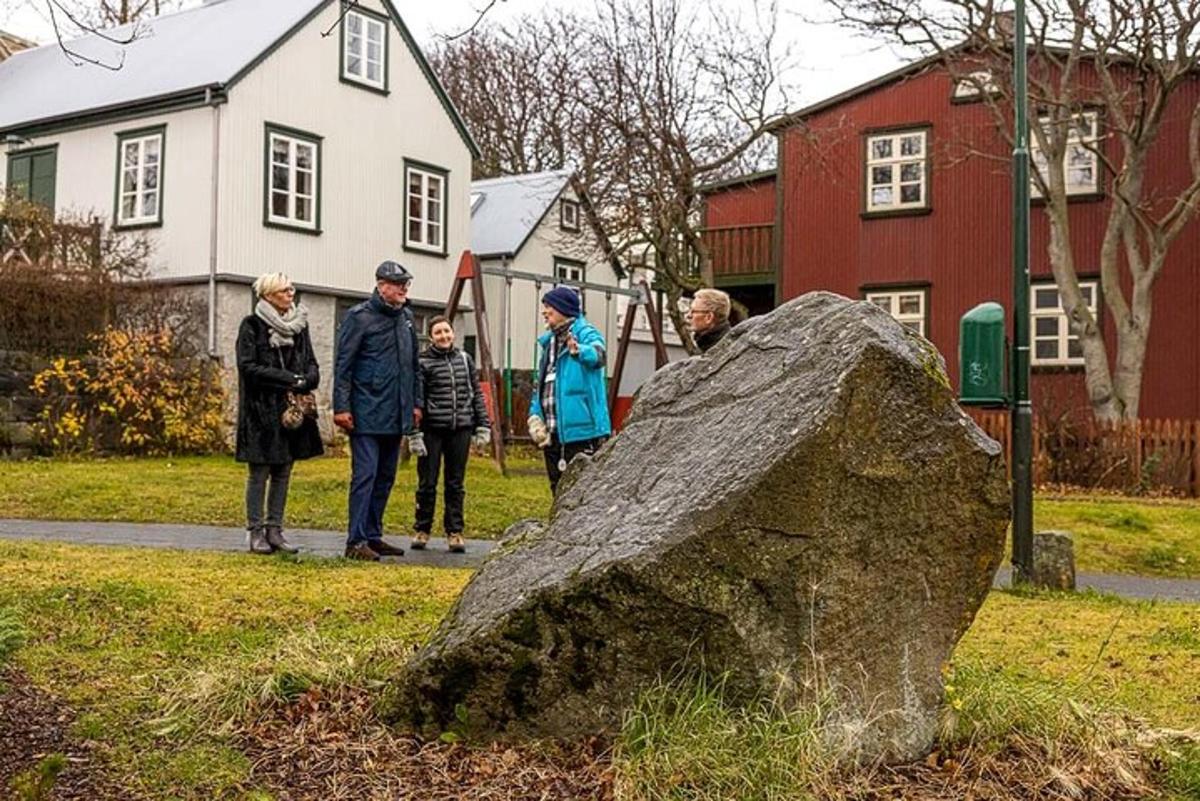 skupina lidí stojících kolem skály v trávě