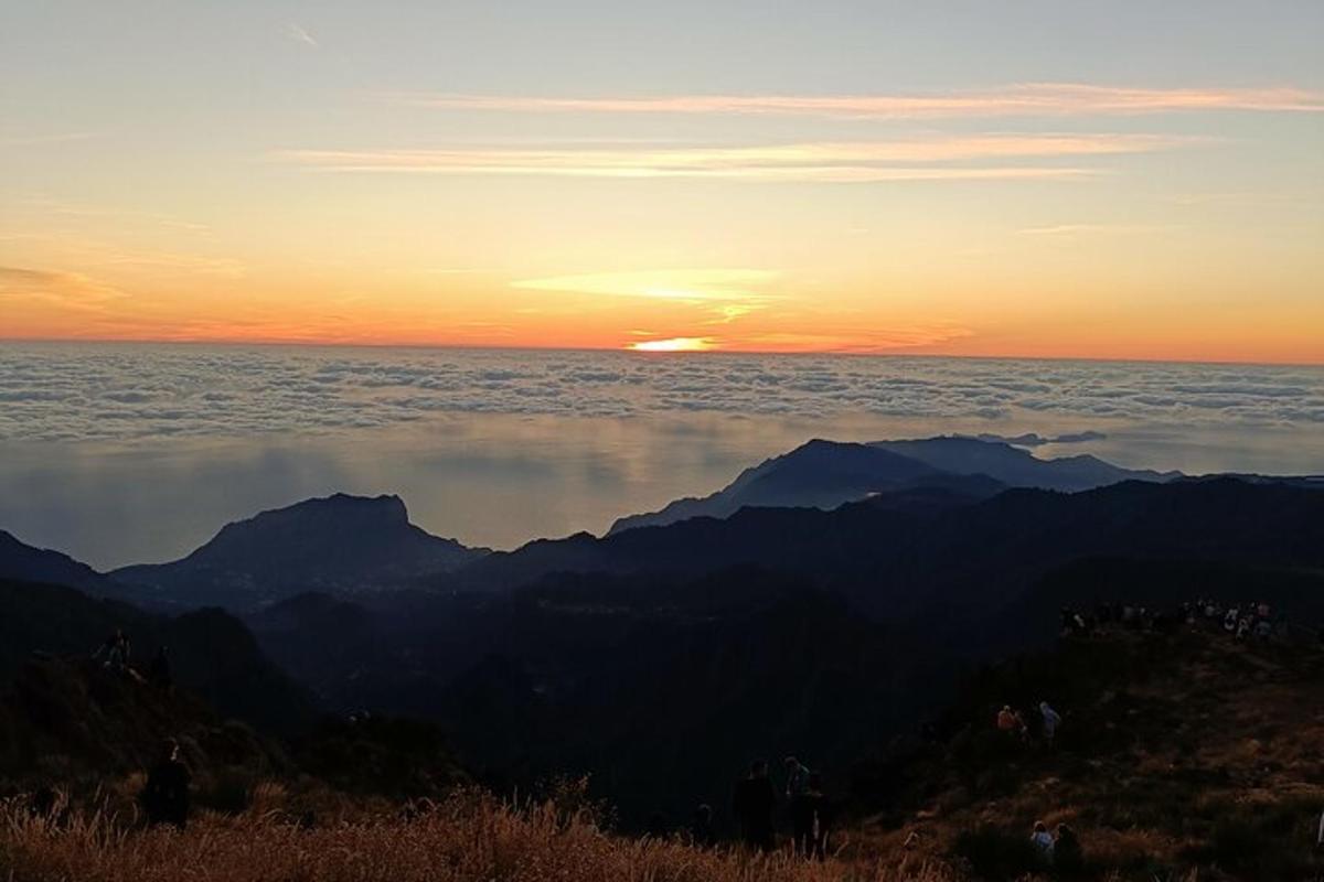 um pôr do sol sobre uma cadeia de montanhas com o sol ao fundo