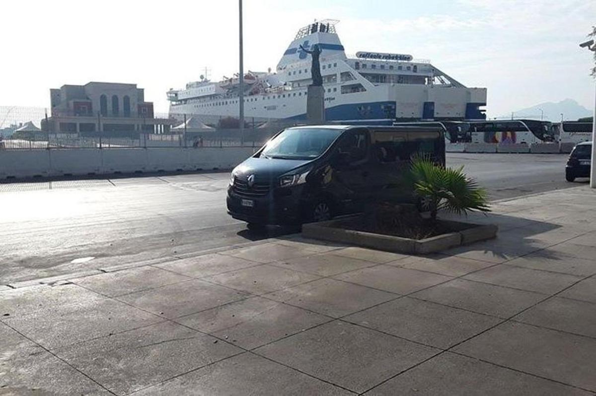 a black van parked in a parking lot with a cruise ship