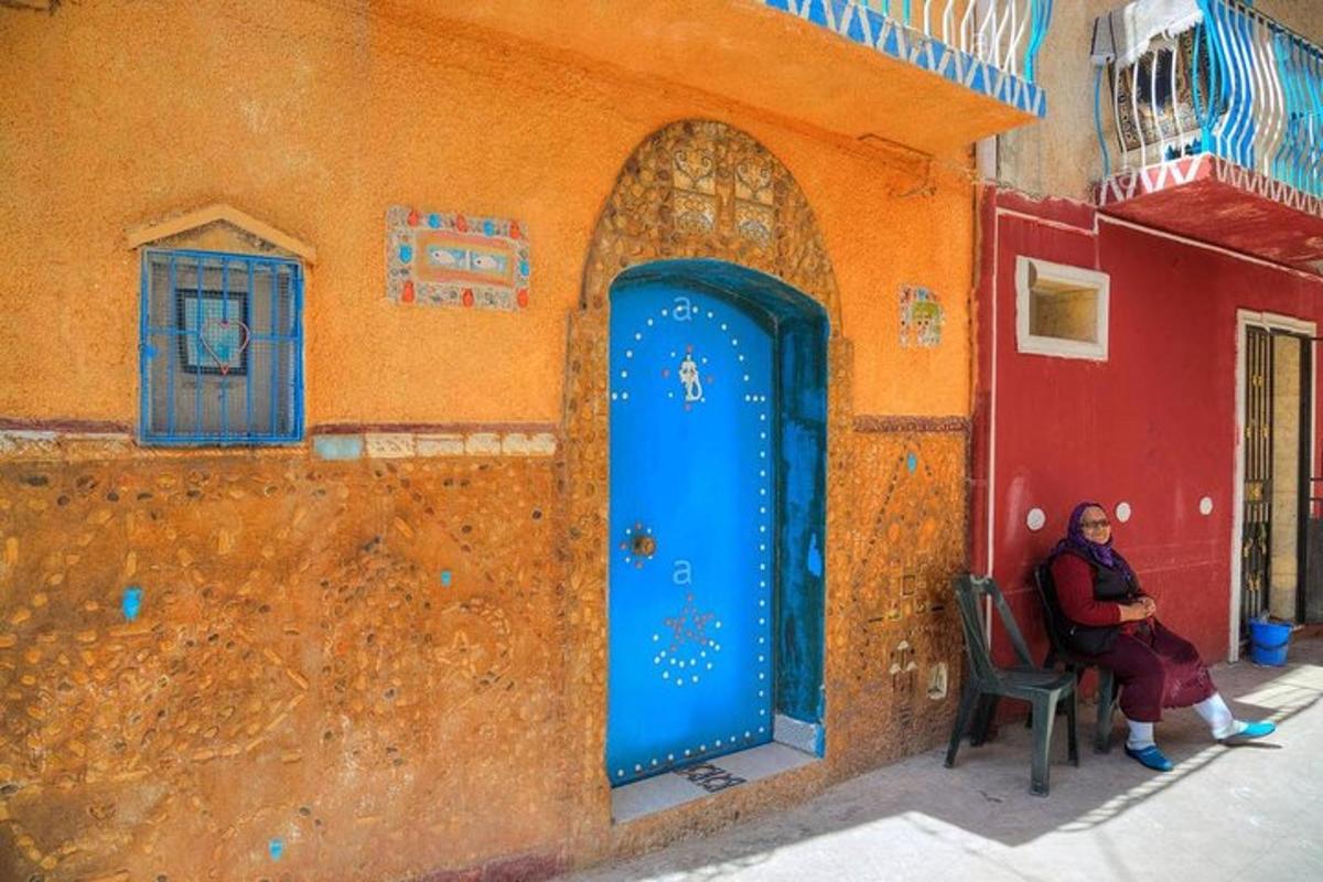 a woman sitting in a chair next to a building with a blue door