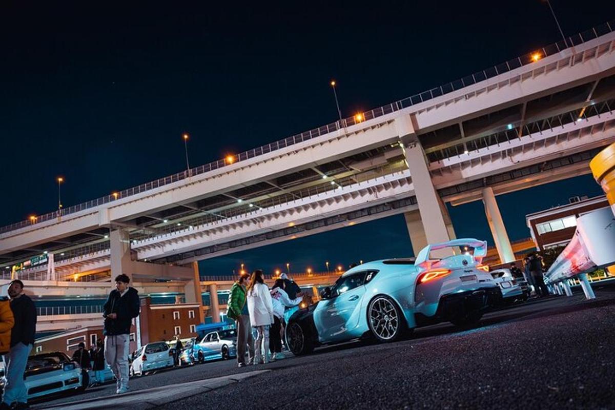 a group of people standing next to a car on the street