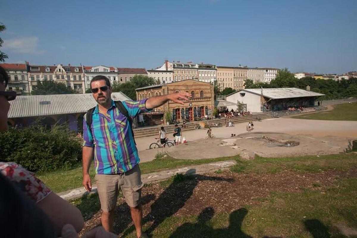um homem parado em um parque com o braço estendido
