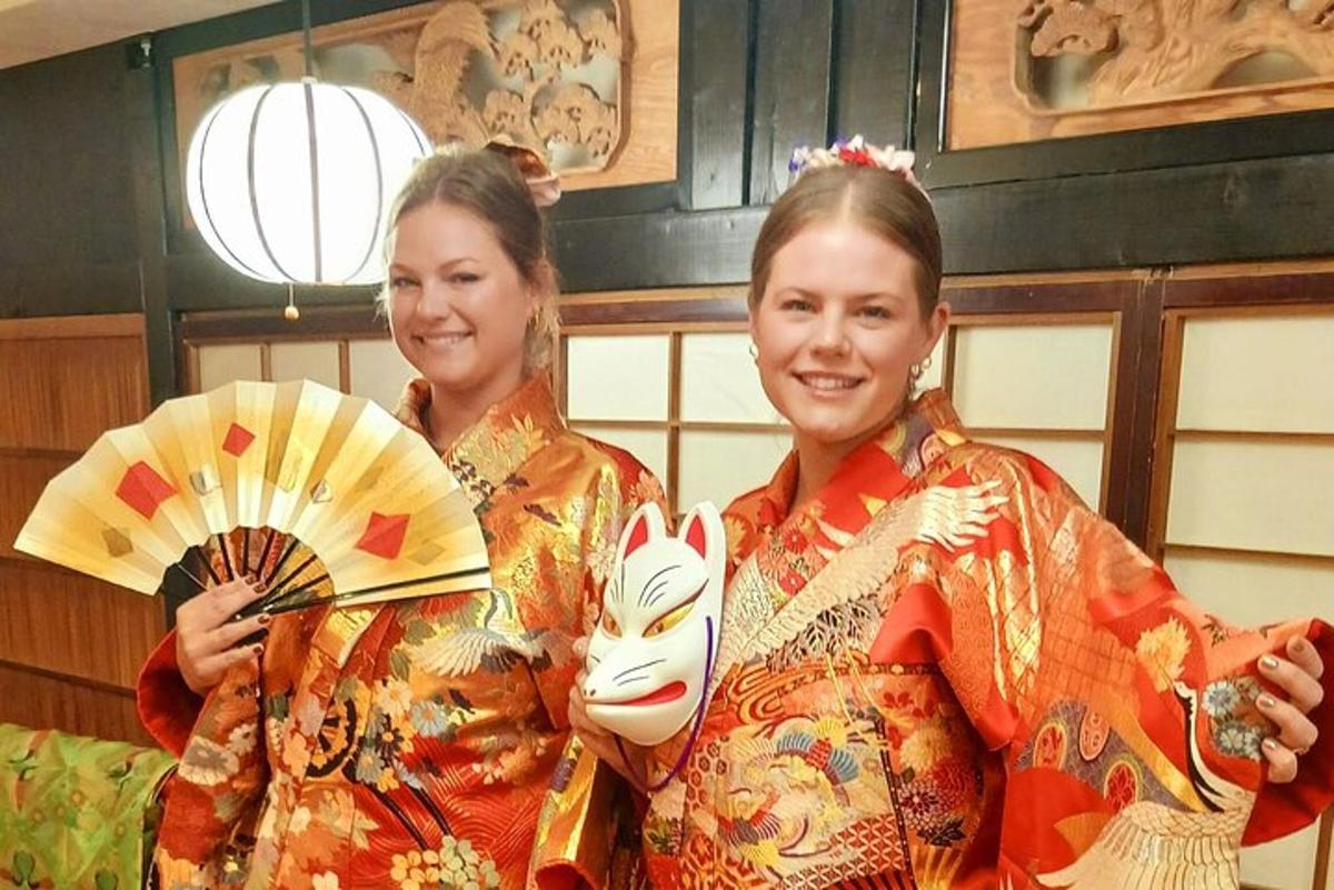 due donne vestite in kimono che tengono un ventaglio