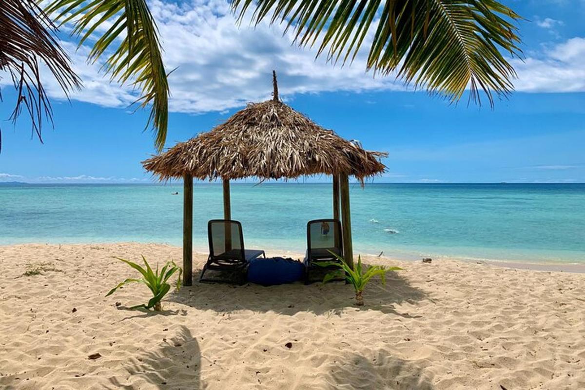 two chairs and a straw umbrella on a beach