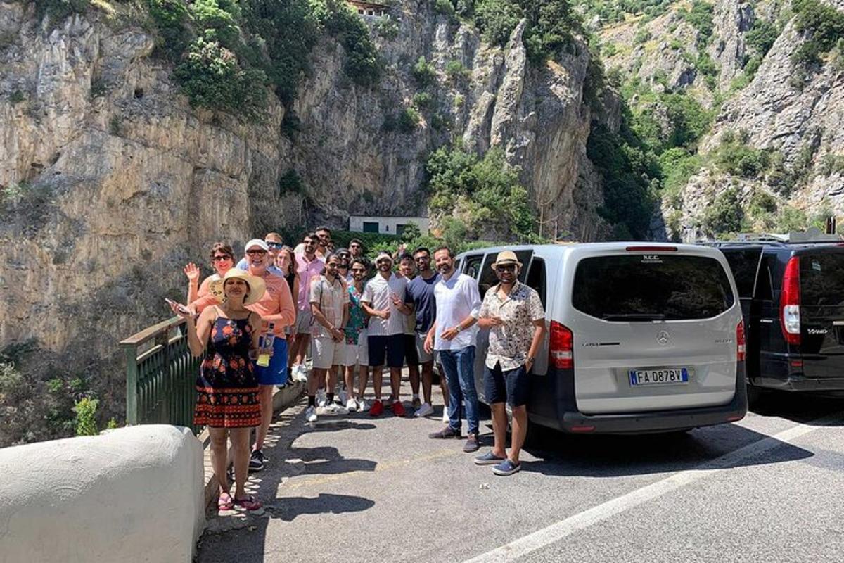 a group of people standing next to a car on a road