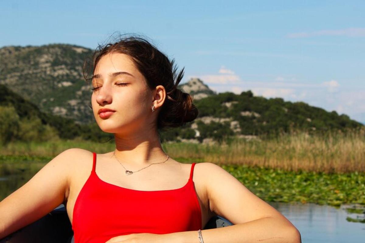 امرأة ترتدي قميصًا أحمر تجلس بجانب نهر