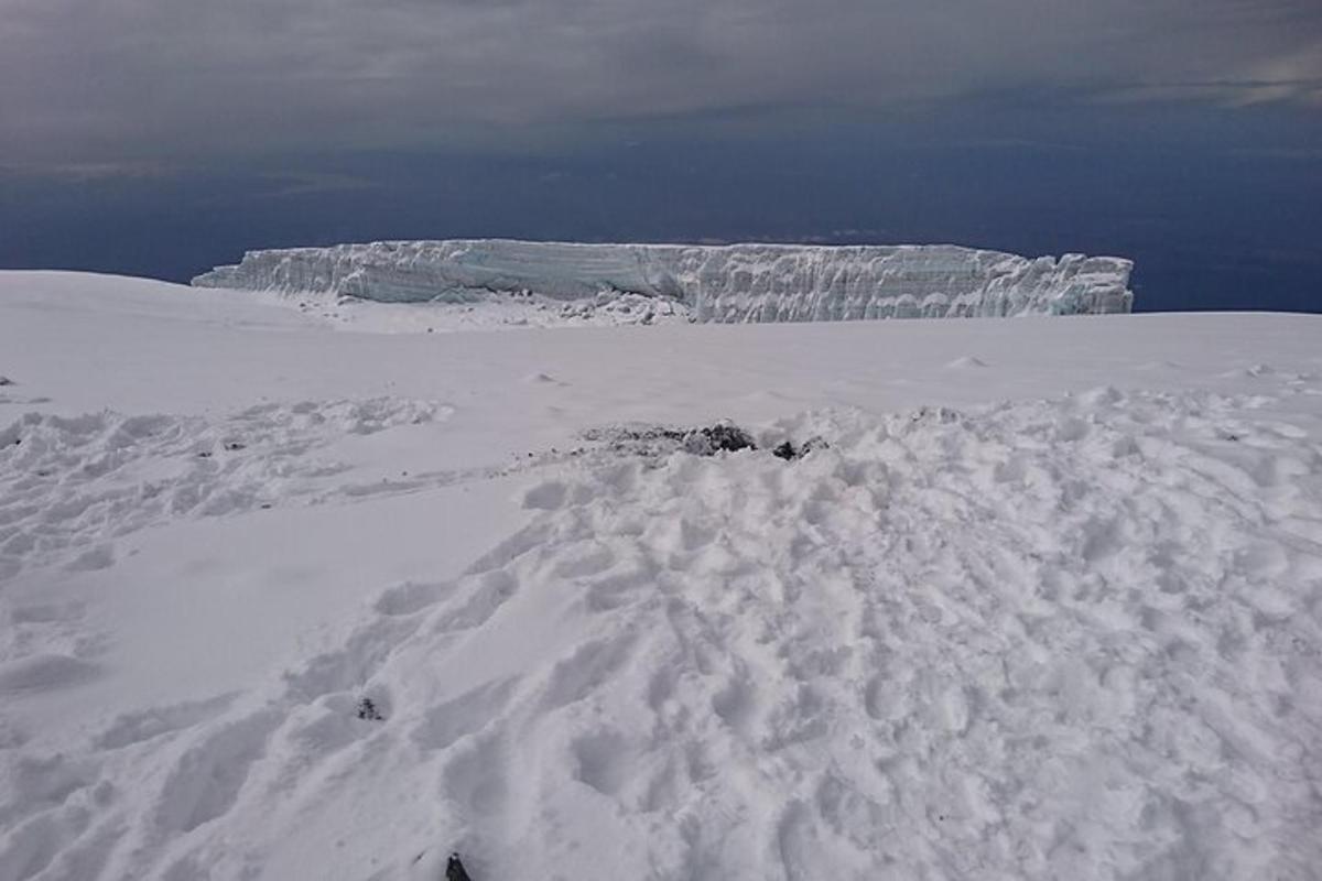 una montagna coperta di neve con un iceberg sullo sfondo