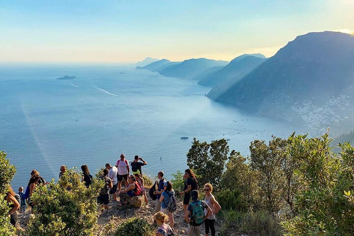 een groep mensen die op een heuvel staat met uitzicht op het water