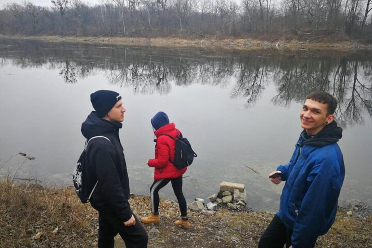 a group of three people walking by a lake