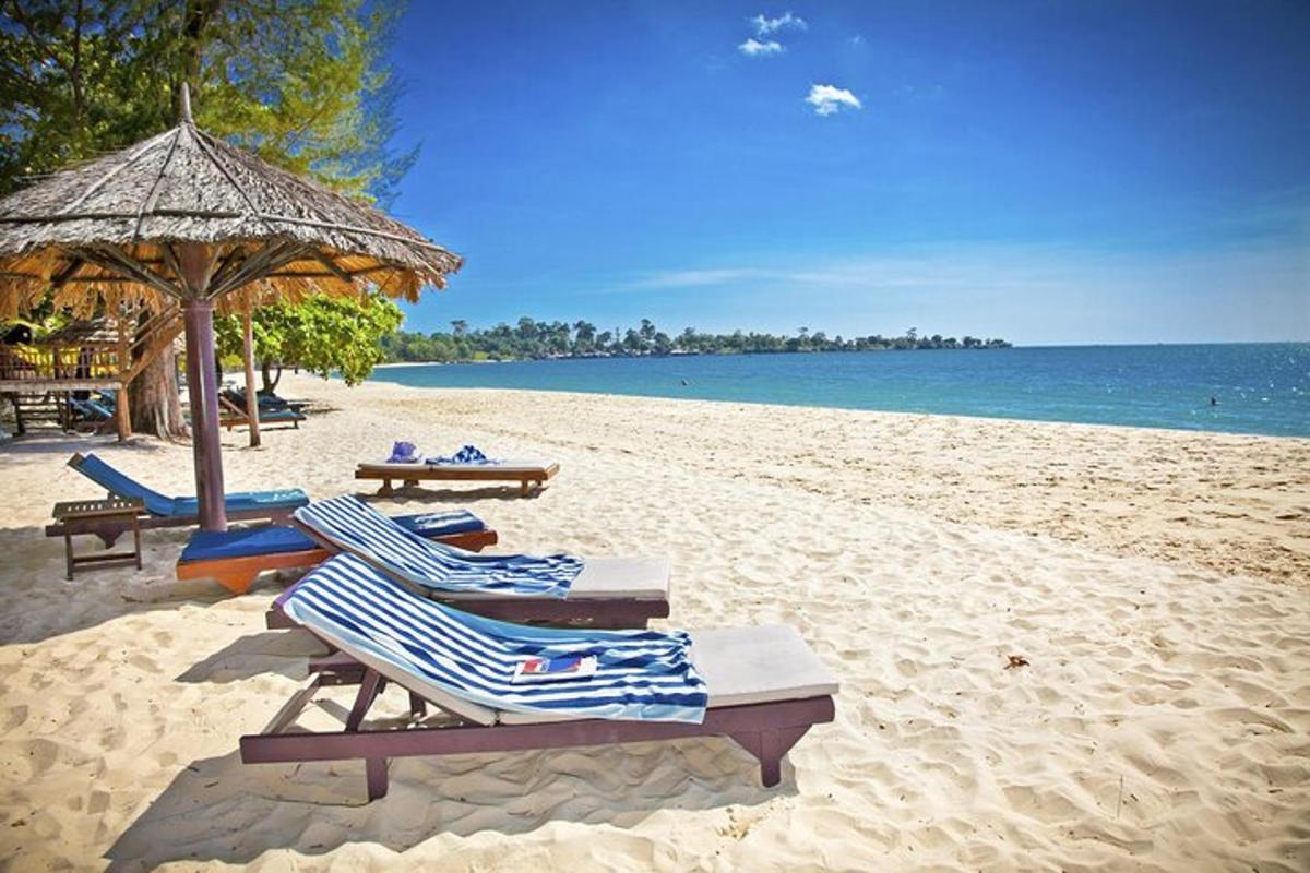 a beach with lounge chairs and an umbrella and the ocean