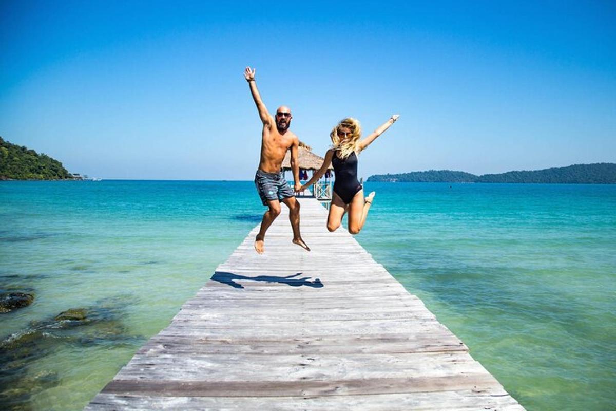a man and woman jumping off a dock into the water