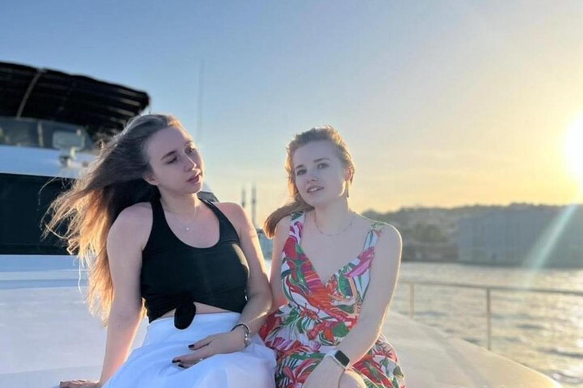 two girls sitting on the edge of a boat