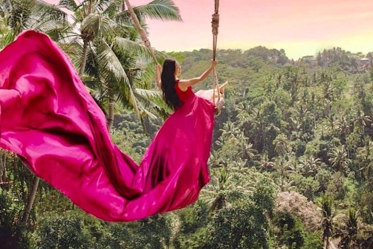 una donna con un vestito rosa che si dondola su un'altalena di corda