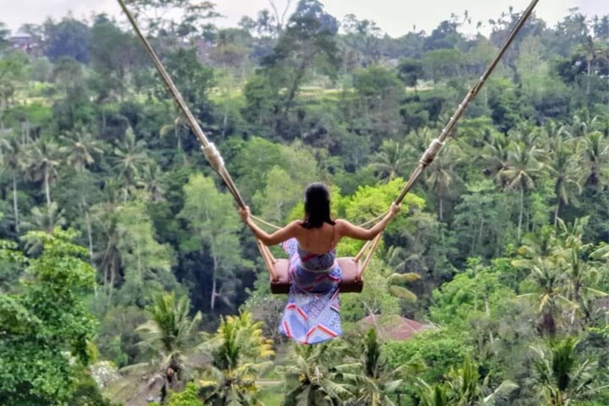 una dona que es balanceja en un gronxador de corda a la selva