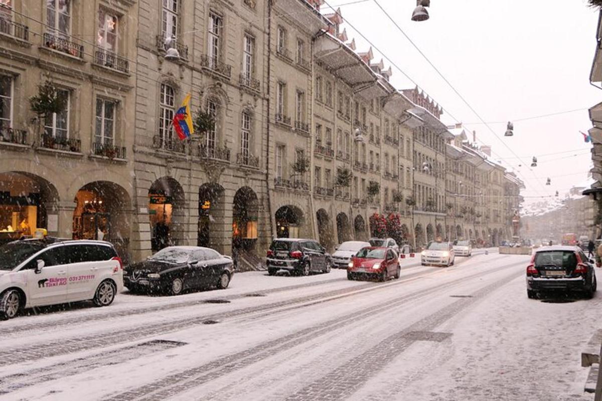 una strada coperta di neve con auto parcheggiate davanti agli edifici