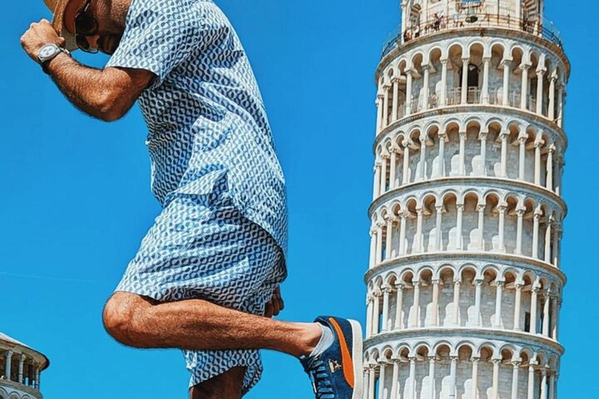 un uomo in piedi accanto alla torre pendente