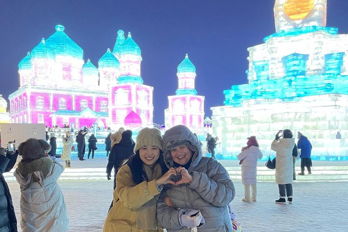 two people posing for a picture in front of an ice rink