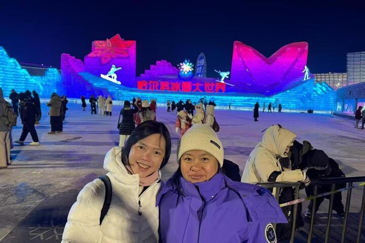 two women standing in front of an ice rink at night