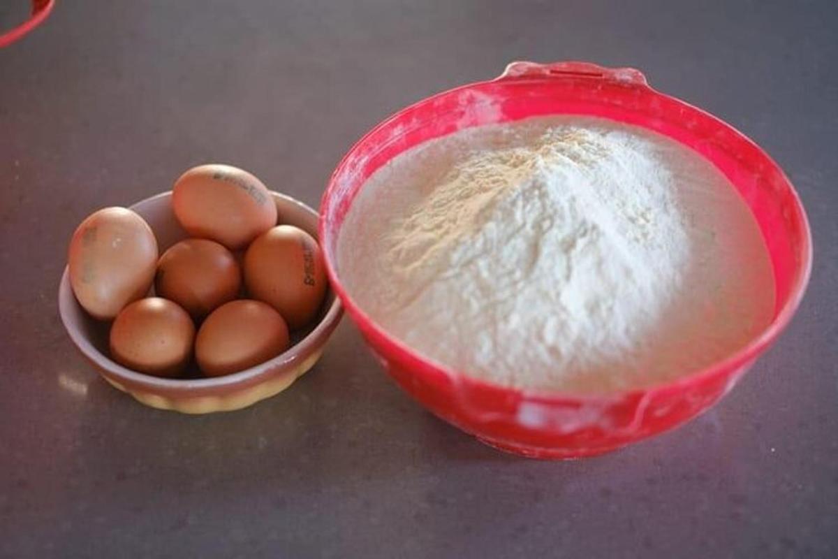 Un tazón rojo de huevos y un tazón de harina