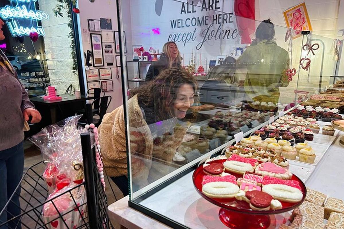 a woman looking at a display case of pastries in a bakery