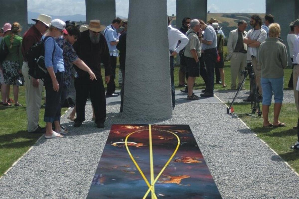 una folla di persone in piedi attorno a un monumento con un cuore sopra