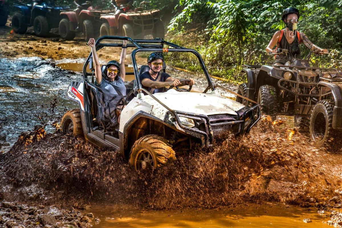 two people in an atv driving through the mud