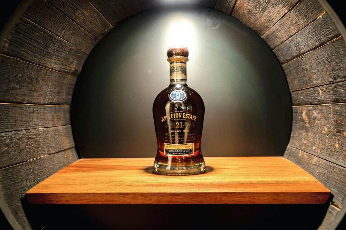 láhev whisky stojící na dřevěné poličce