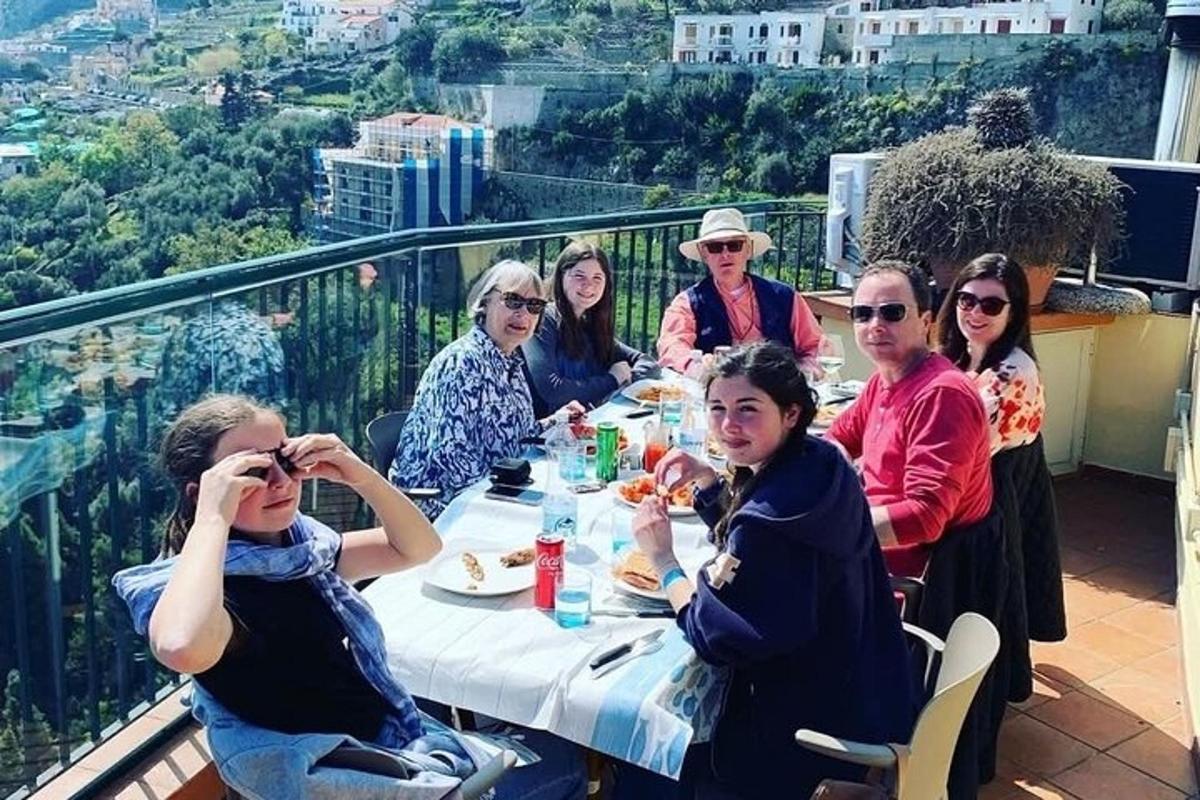 μια ομάδα ανθρώπων που κάθονται σε ένα τραπέζι σε ένα μπαλκόνι