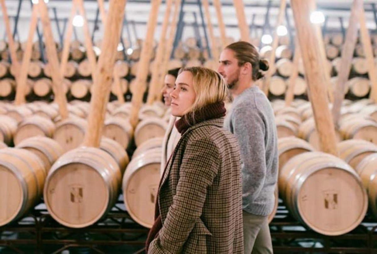 a group of people walking through a wine cellar