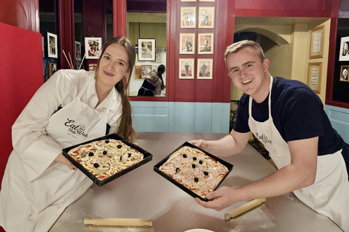 muž a žena v kuchyni drží pizzy