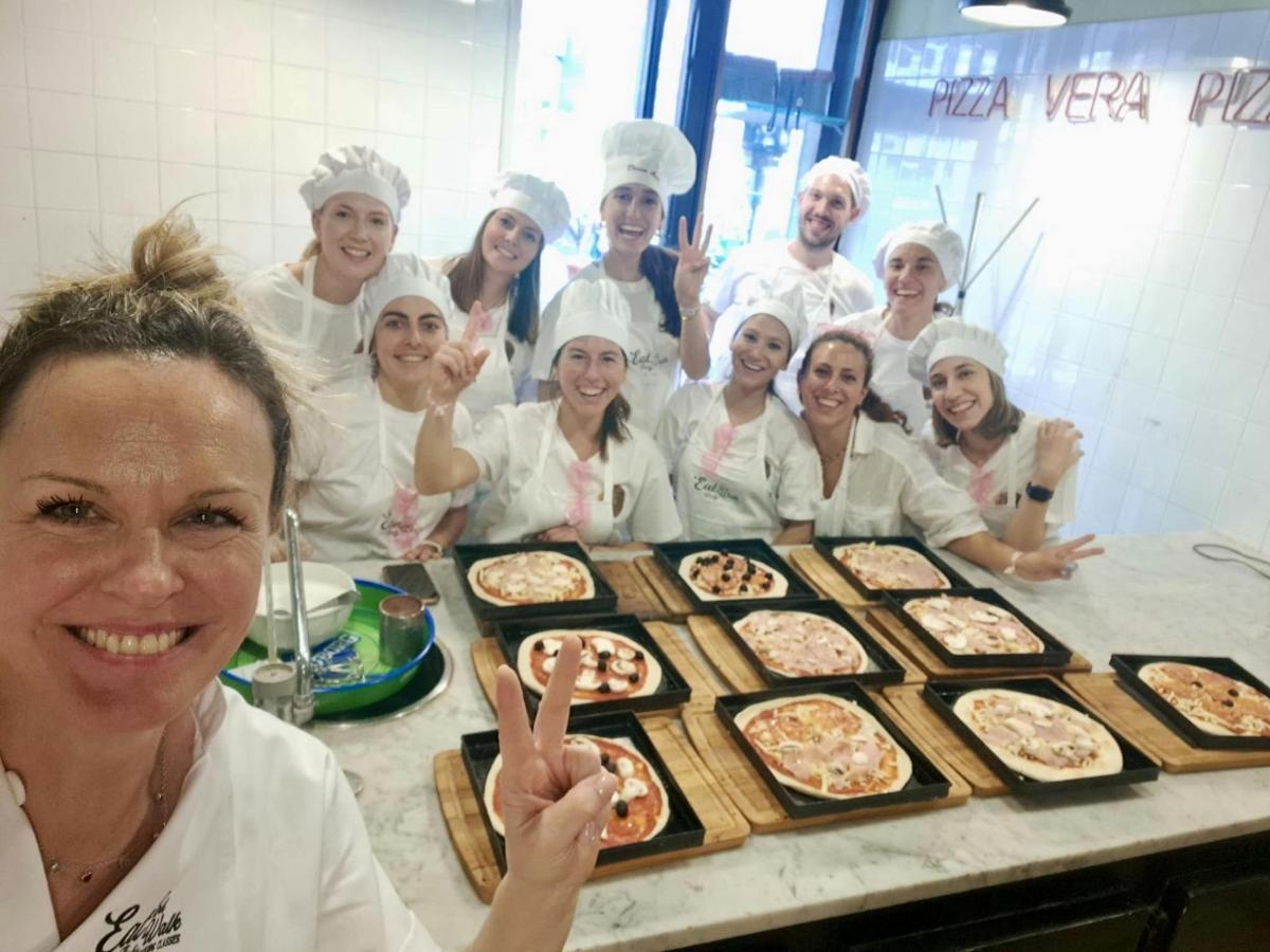 Skupina kuchařů stojících před stolem s pizzami
