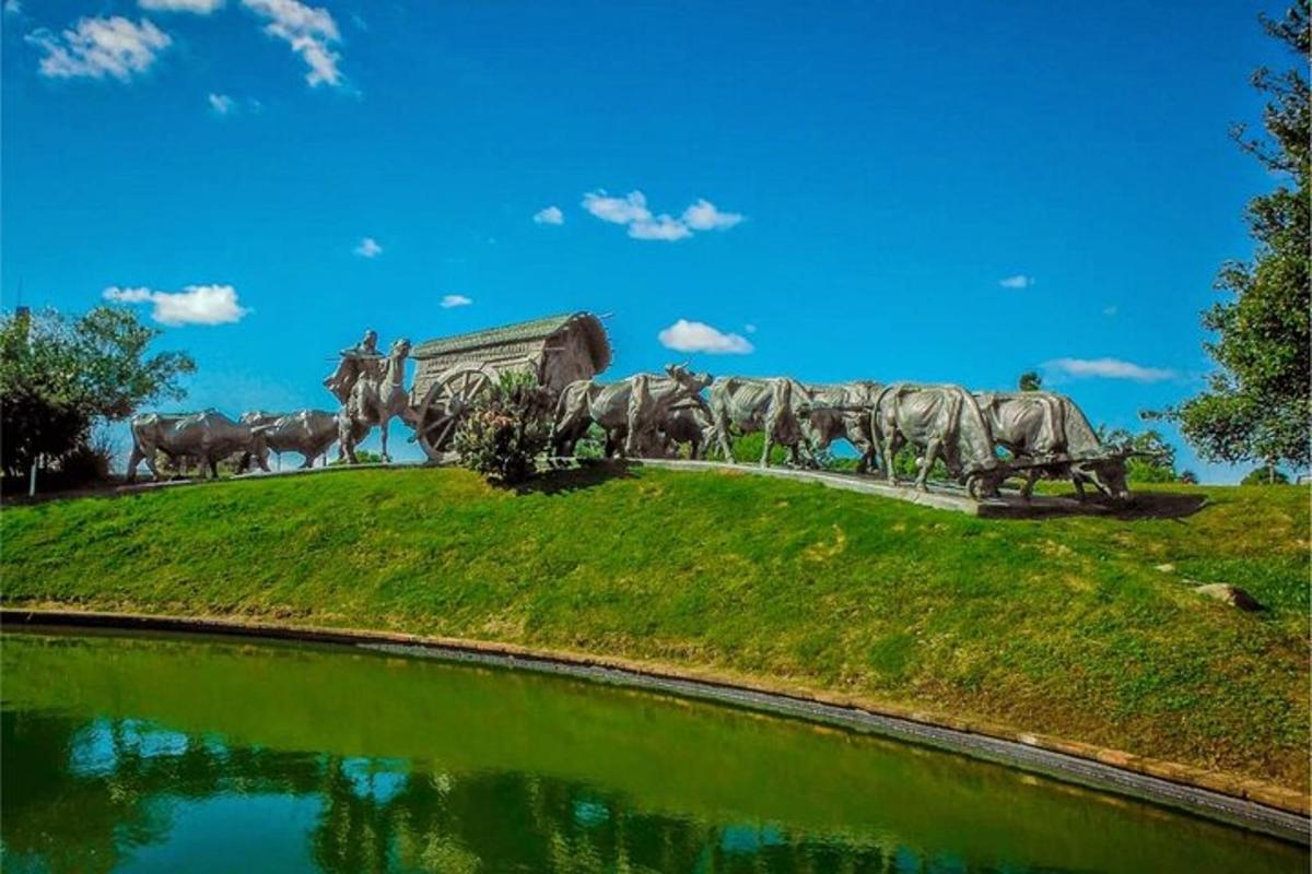 uma estátua de cavalos em uma colina próxima a um lago