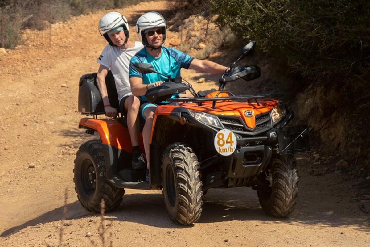 two people are riding on a atv on a dirt road
