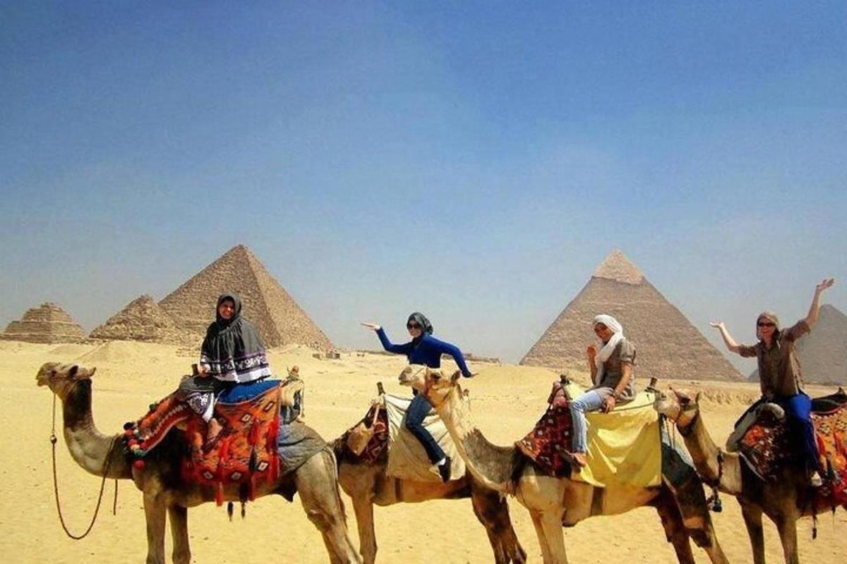 a group of people riding on camels in front of the pyramids