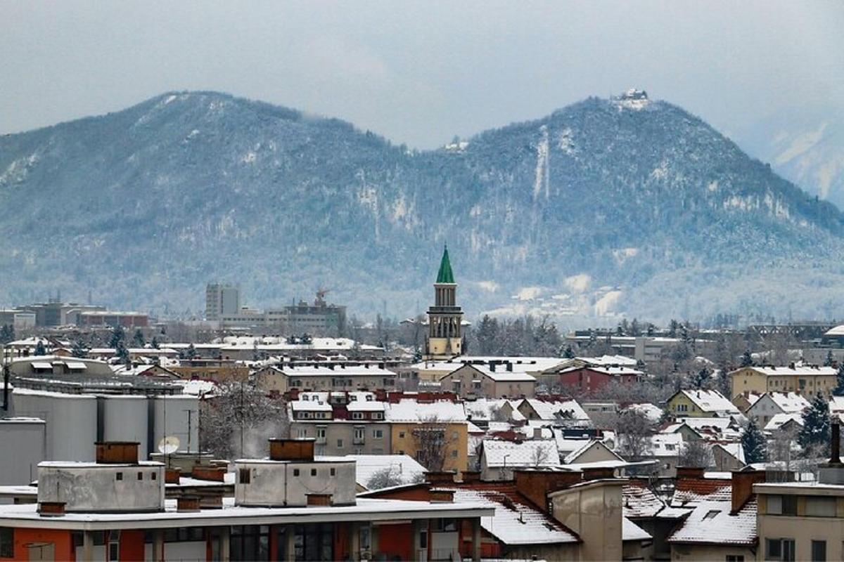 a city with snow covered buildings and a mountain