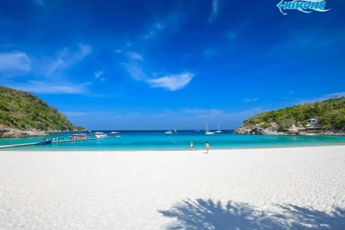 seseorang yang berdiri di pantai putih dengan air biru